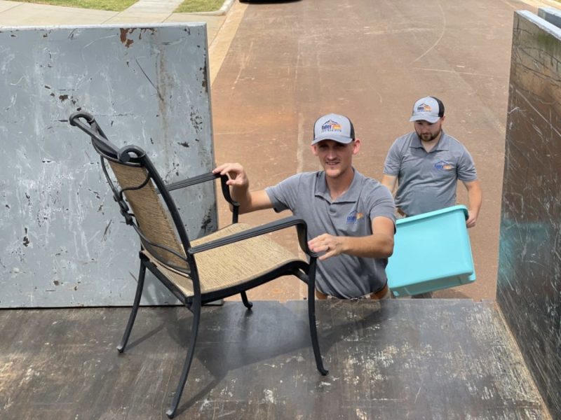 junk removal pros moving chairs into truck