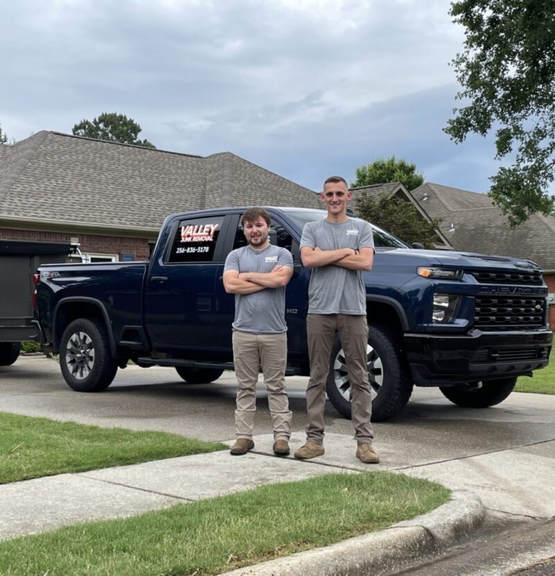 Two Valley Junk Removal crew smiling in front of a blue truck ready to pick up junk