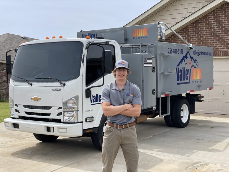 Valley Junk Removal team member smiling next to the company truck ready to provide junk removal services