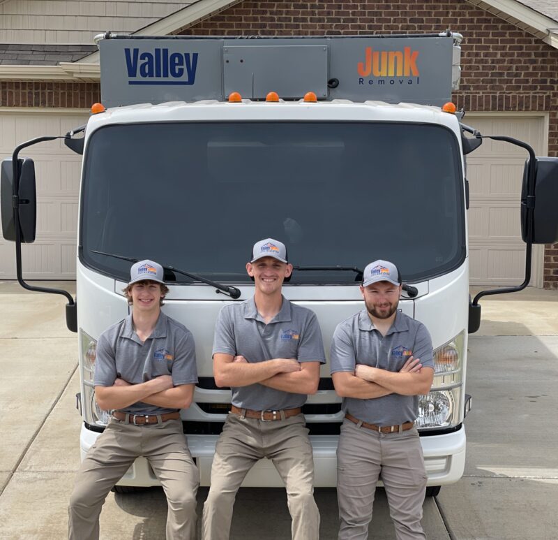 Valley Junk Removal professionals smiling next to the truck ready to provide tire hauling services