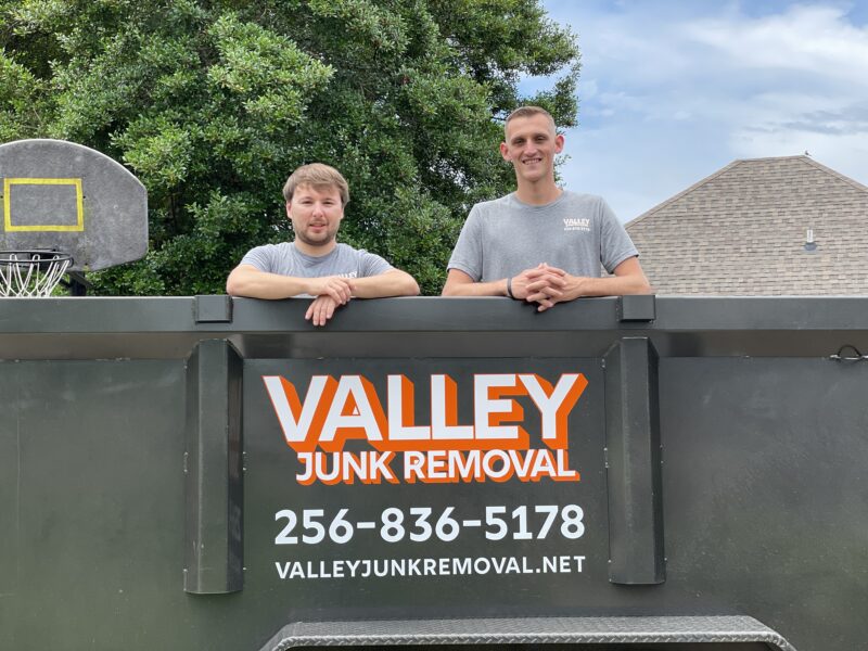 Junk removal professionals smiling in the bed of their truck