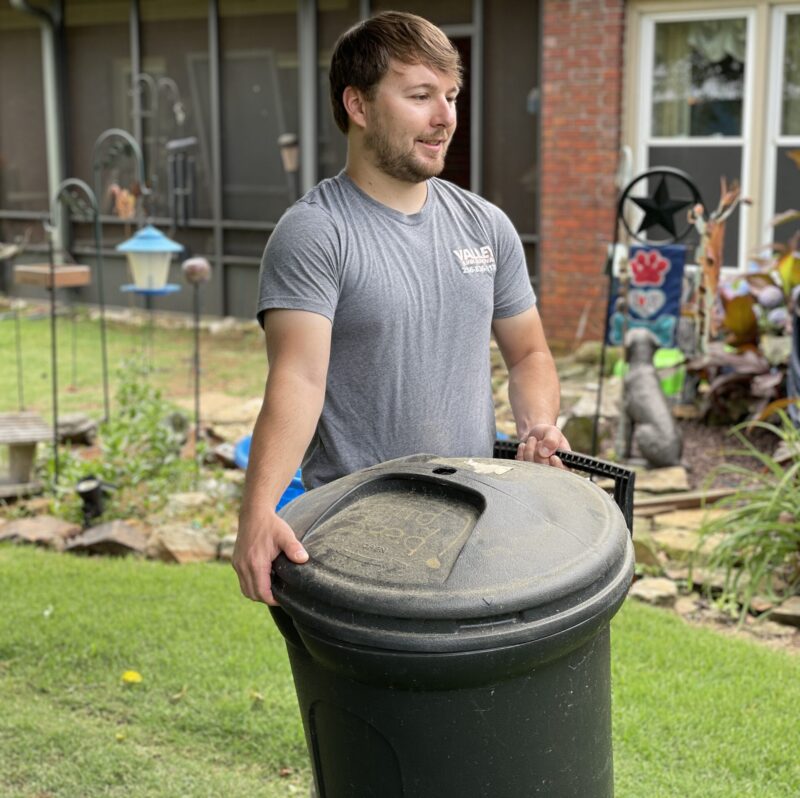 Junk removal professional carrying a trash bin to the truck during garbage removal services